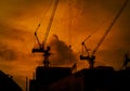 Construction cranes on high-rise building with dramatic orange sky and clouds at sunset time in the evening. Construction site Royalty Free Stock Photo