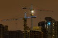 Construction cranes with LED backlight on a construction site of apartment buildings at night in winter