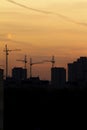 Construction cranes near residential apartments - view on sunrise, vertical Royalty Free Stock Photo