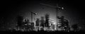 Construction cranes standing silhouetted against a night-time cityscape, AI-generated.
