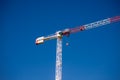 Construction cranes work on creation site against blue sky background. Bottom view of industrial crane. Copy space Royalty Free Stock Photo