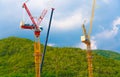 Construction cranes work on creation site against blue sky and mountains Royalty Free Stock Photo