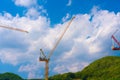 Construction cranes work on creation site against blue sky and mountains Royalty Free Stock Photo