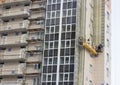 Construction decoration work of the facade by builders in a construction cradle of new residential buildings and tower cranes Royalty Free Stock Photo