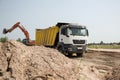 construction dump truck with a yellow body and an orange crawler excavator next to each other while working in a quarry