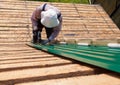 Construction elderly worker install new roof, Roofing tools, Electric drill used on new roofs with Metal Sheet. Self-made house by Royalty Free Stock Photo