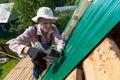 Construction elderly worker install new roof, Roofing tools, Electric drill used on new roofs with Metal Sheet. Self-made house by Royalty Free Stock Photo