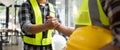 Construction engineer and architect with blueprint shaking hands while standing on construction site. Home building Royalty Free Stock Photo