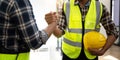 Construction engineer and architect with blueprint shaking hands while standing on construction site. Home building Royalty Free Stock Photo