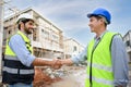 Construction engineer and architect with blueprint shaking hands while standing on construction site. Home building concept Royalty Free Stock Photo