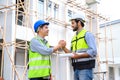 Construction engineer and architect with blueprint shaking hands while standing on construction site. Home building concept Royalty Free Stock Photo