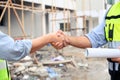 Construction engineer and architect with blueprint shaking hands while standing on construction site. Home building concept Royalty Free Stock Photo