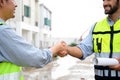 Construction engineer and architect with blueprint shaking hands while standing on construction site. Home building concept Royalty Free Stock Photo