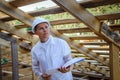 Construction engineer or architect with blueprints on building site of wood frame house. Portrait of a man in a white helmet with Royalty Free Stock Photo