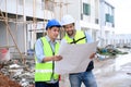 Construction engineer and architect check plan working with the blueprint on construction site. They are in safety vests with Royalty Free Stock Photo