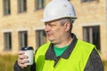 Construction Engineer with cup of coffee near building