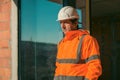 Construction engineer with protective white helmet and high visibility orange jacket on site Royalty Free Stock Photo