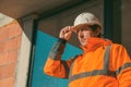 Construction engineer with protective white helmet and high visibility orange jacket on site Royalty Free Stock Photo