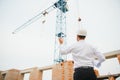 Construction engineer supervising progress of construction project stand on new concrete floor top roof and crane Royalty Free Stock Photo