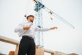 Construction engineer supervising progress of construction project stand on new concrete floor top roof and crane Royalty Free Stock Photo