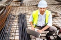 construction engineer working on laptop, wearing safety equipement and coordinating workers