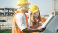 Construction site engineers and architects with safety helmet with building background with the plan or blueprint of the project Royalty Free Stock Photo
