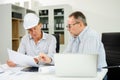 Construction engineers discussing plans with blueprints and digital tablet. Safety, teamwork, planning, and architecture Royalty Free Stock Photo