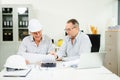 Construction engineers discussing plans with blueprints and digital tablet. Safety, teamwork, planning, and architecture Royalty Free Stock Photo