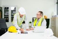Construction engineers discussing plans with blueprints and digital tablet. Safety, teamwork, planning, and architecture Royalty Free Stock Photo
