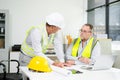 Construction engineers discussing plans with blueprints and digital tablet. Safety, teamwork, planning, and architecture Royalty Free Stock Photo