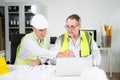 Construction engineers discussing plans with blueprints and digital tablet. Safety, teamwork, planning, and architecture Royalty Free Stock Photo