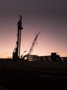 Construction equipment silhouetted against evening sky