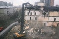 Construction equipment destroys a house on the site. Dismantling and demolition of a building in the city. The wreckage