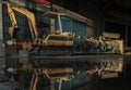 Construction excavator of yellow color and Old waters pumps with reflection on water Royalty Free Stock Photo