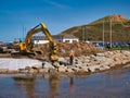 The construction of flood defences using heavy earth moving equipment and large stone blocks