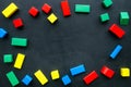 Construction game for kids. Wooden building blocks, toy bricks on black background top view space for text frame Royalty Free Stock Photo