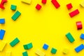 Construction game for kids. Wooden building blocks, toy bricks on yellow background top view space for text frame Royalty Free Stock Photo