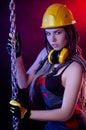 A construction girl in a hard hat and overalls with a long chain in her hands