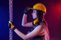 A construction girl in a hard hat and overalls with a long chain in her hands