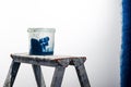 Construction grunge ladder, paint roller and paint bucket in white interior: white wall and gray floor Royalty Free Stock Photo