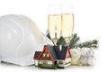 Construction hard hat, fir tree branches, model house, two glasses with champange and Christmas ornament isolated on a white Royalty Free Stock Photo