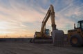 Construction heavy hydraulics equipment excavator shovel yellow machine earth movers sunset clouds Royalty Free Stock Photo