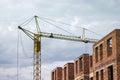 Construction of high brick house with a crane.