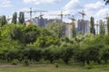 Construction of a high-rise building, construction crane. Green trees in the foreground
