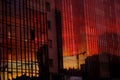 Construction of a high-rise house. Cranes reflected in the windows of a skyscraper. Concept of new buildings