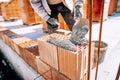 Construction industry details - worker bricklayer building exterior walls with mortar and bricks