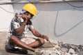 A construction labour working with hammer and Chisel wearing safety helmet in a construction site Royalty Free Stock Photo