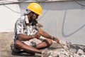 A construction labour working with hammer and Chisel wearing safety helmet in a construction site Royalty Free Stock Photo