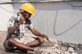 A construction labour working with hammer and Chisel wearing safety helmet in a construction site Royalty Free Stock Photo