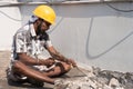 A construction labour working with hammer and Chisel wearing safety helmet in a construction site Royalty Free Stock Photo